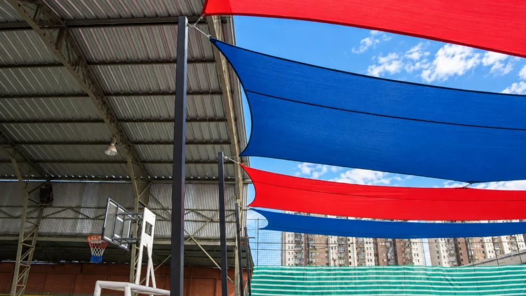Toldos vela rojos y azules instalados junto a la cancha de Denver School
