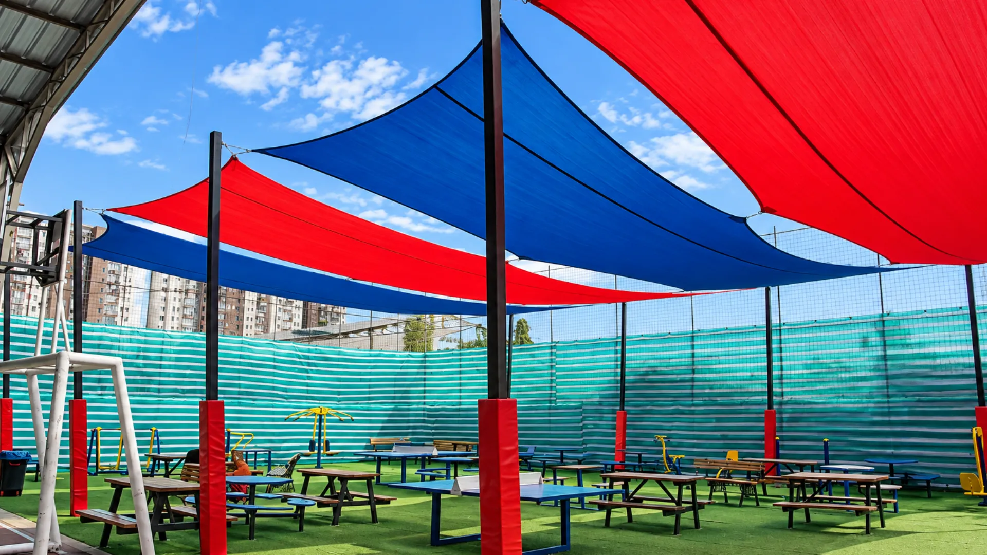 Patio de Denver School con toldos vela, mesas y protectores rojos en los pilares